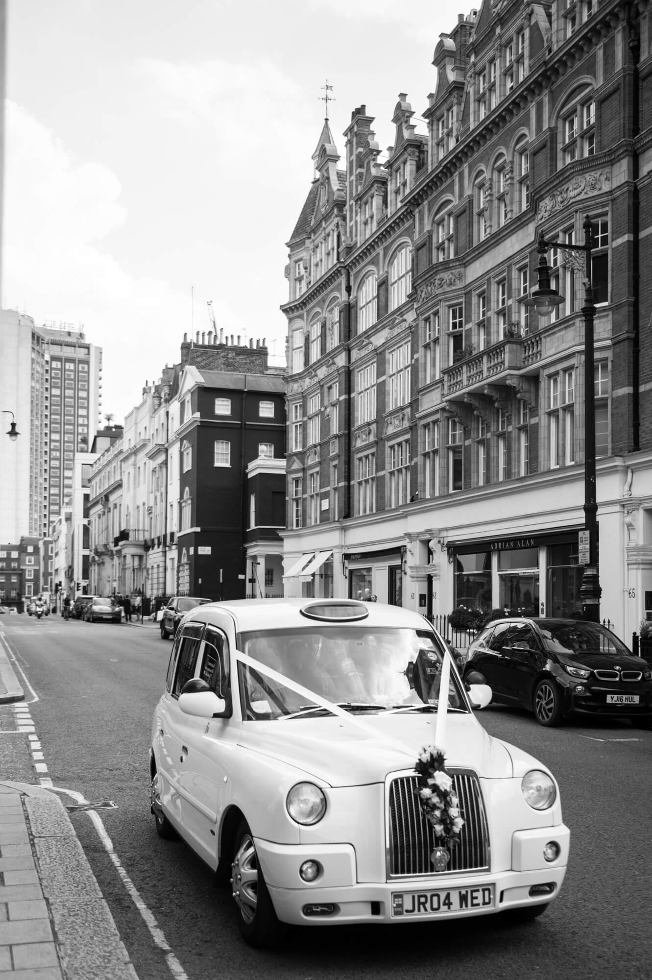 A white London taxi with wedding ribbon in the city